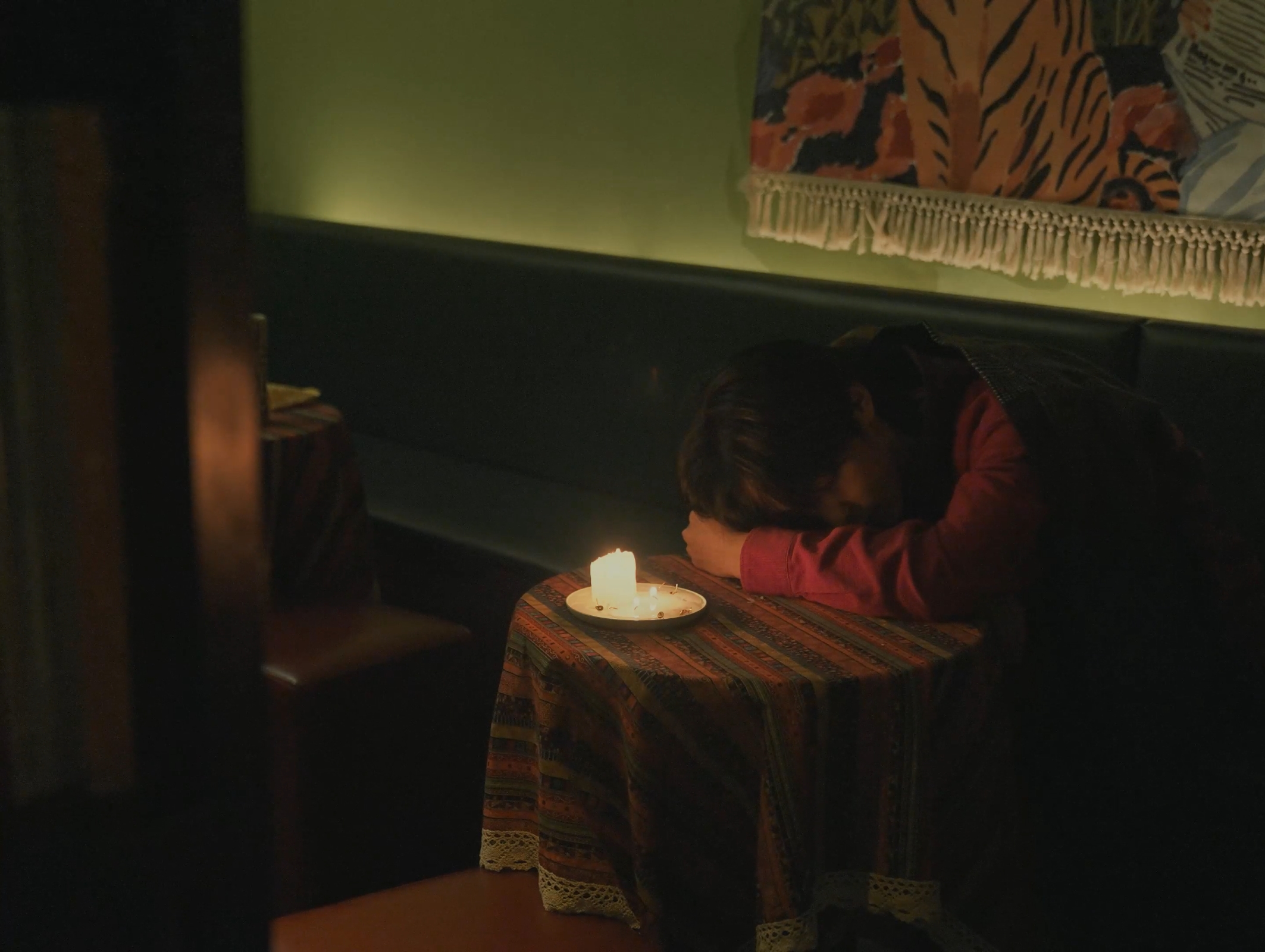 Still frame of a man resting his head on a table.